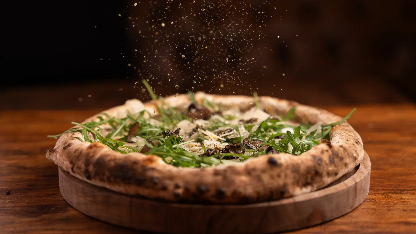 Une Tartufo sur sa planche, la truffe tombe en pluie sur la roquette et le parmesan